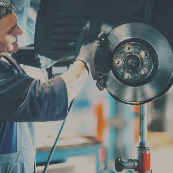 tech fixing brakes on a car